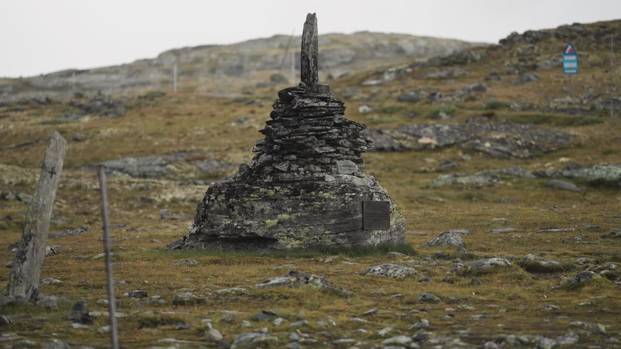 A dark weather-worn stone cairn in the bleak autumn tundra. Parallax shot.