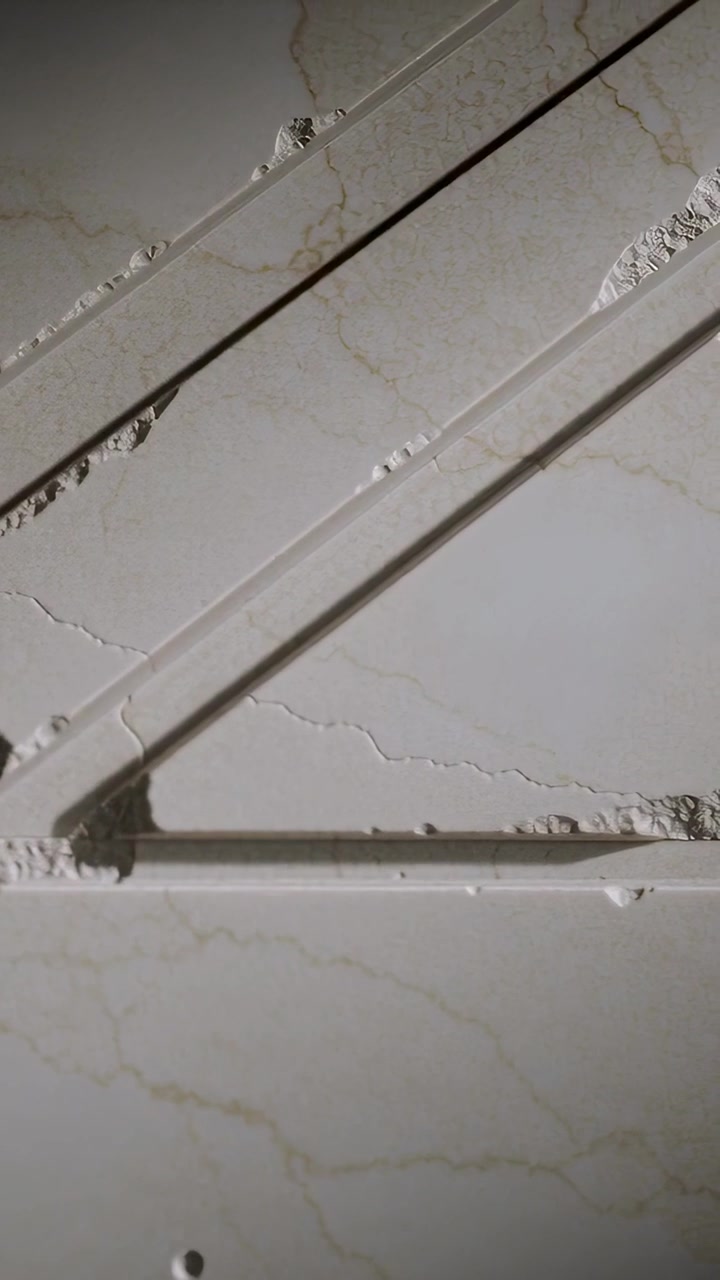 Vertical video: Shifting camera inspecting damaged marble panel in restroom, showing chip and hole