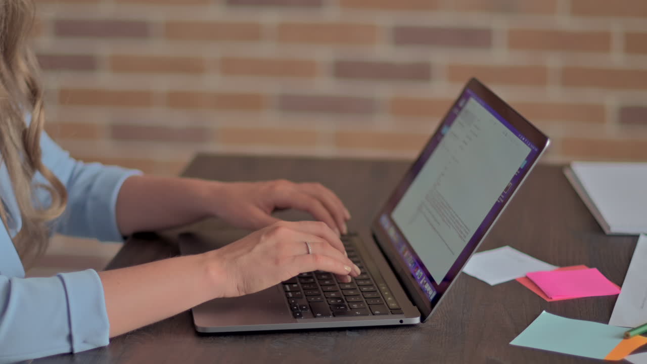 Mulher de blazer azul digitando em um laptop em uma mesa de escritório