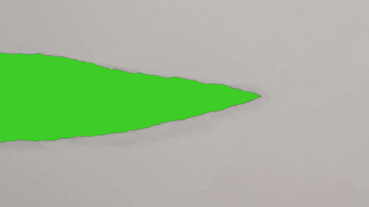 cerca de la mano arrancando una tira de papel descubriendo el fondo de la pantalla verde debajo