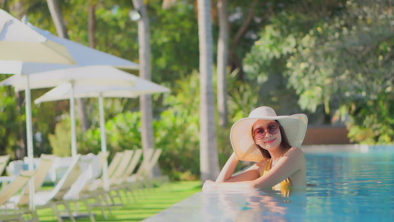 A pretty young woman in a resort pool looks up and smiles