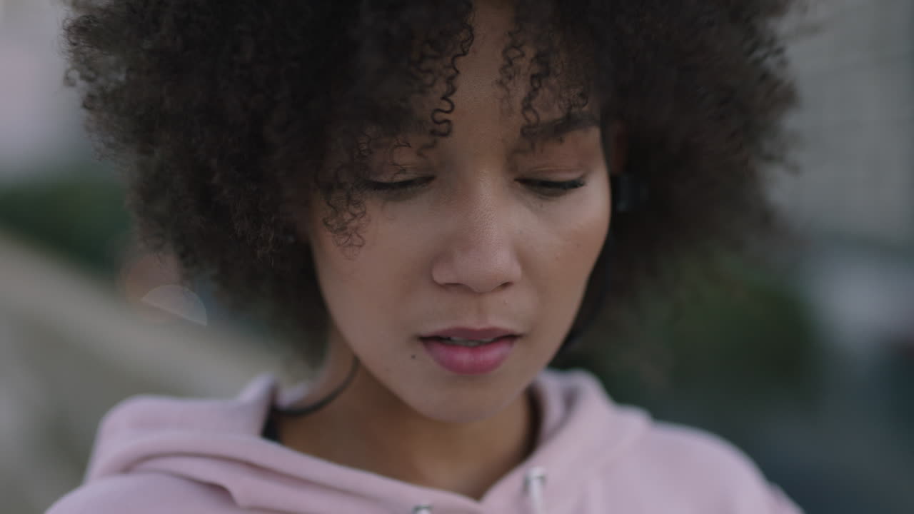 close up portrait beautiful mixed race woman wearing earphones enjoying listening to music smiling happy looking at camera wind blowing afro hairstyle