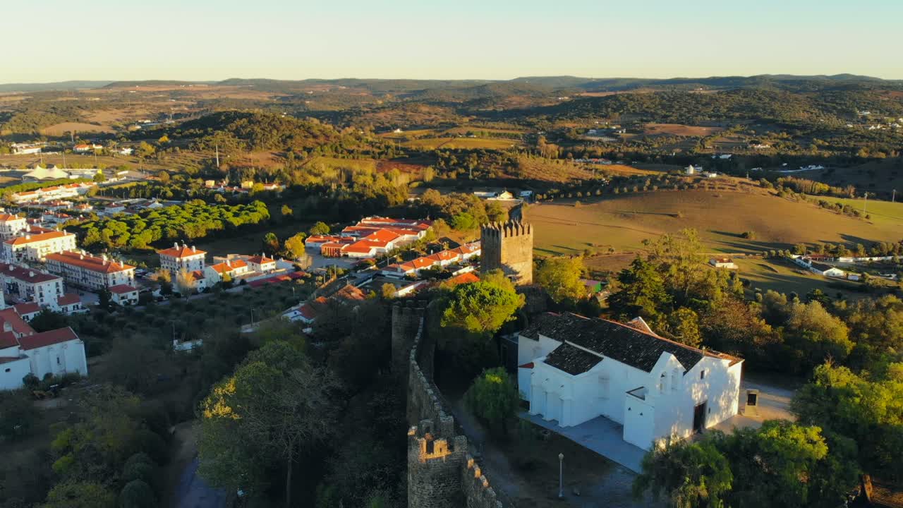 Portekiz'in Alentejo bölgesinde, ortaçağ duvarı ve kulesi olan bir tepedeki beyaz şapel binasının drone çekimi.