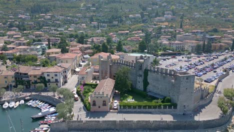 Tiro-Aéreo-Circular-Al-Castillo,-Más-Cerca,-Tiro-Largo-Sobre-El-Castillo-De-Castello-Scaligero-En-El-Lago-De-Garda-En-Italia