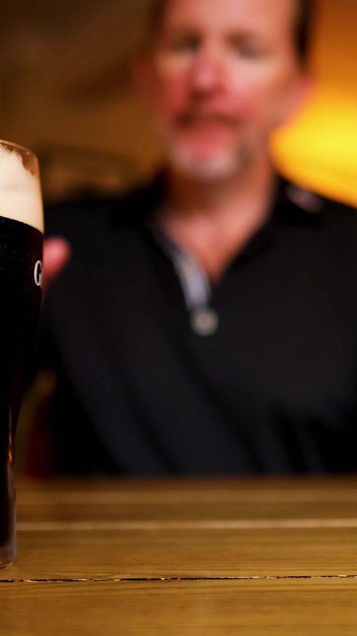 Uomo beve birra stout in un pub