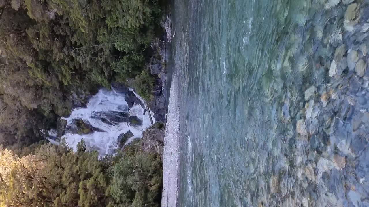 Vertical view of the picturesque fantail falls with the glacial fed river in front surrounded by native bush in the west coast of New Zealand