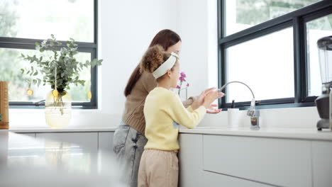 mother and daughter washing hands in the kitchen