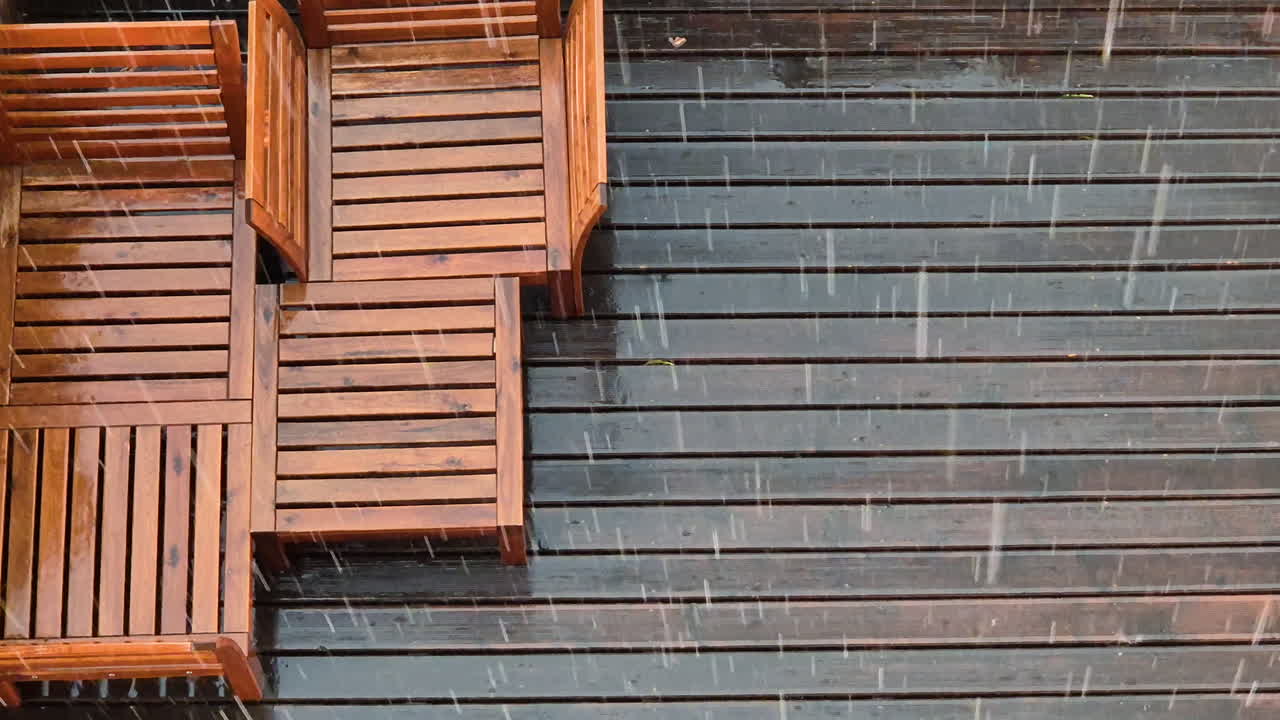lluvia fuerte cae sobre bancos de madera y cubiertas