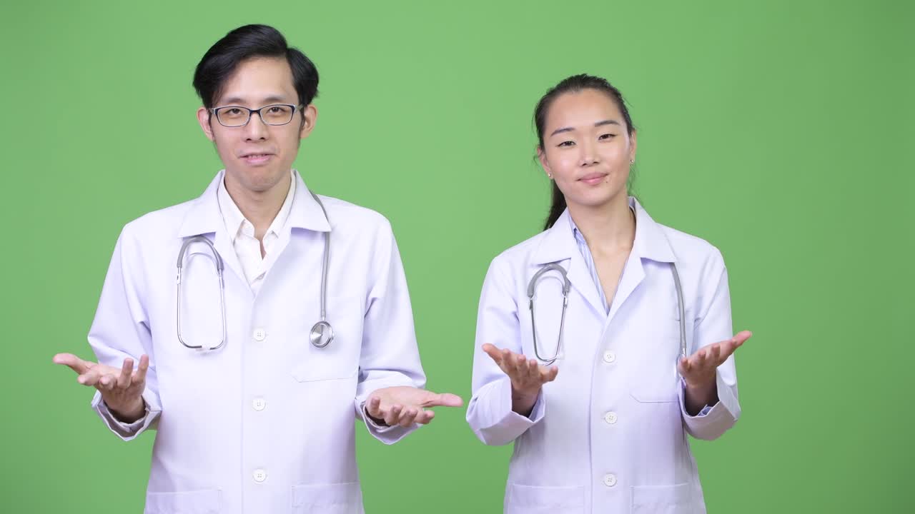 Young Asian couple doctors shrugging together