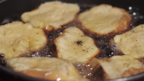 golden round pieces of old bread frying on hot skillet to make rabanadas - close up