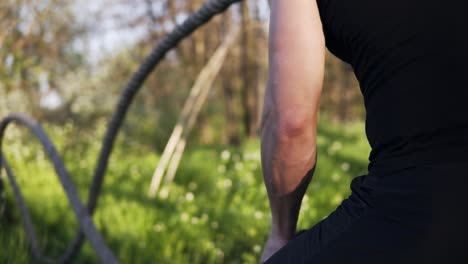 apuntando imágenes de un hombre con los brazos agitando cuerdas de batalla. crossfit. entrenamiento. primavera. al aire libre