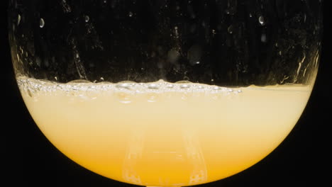 Fresh-orange-juice-with-small-bubbles-bursting-in-glass