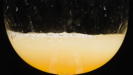 fresh orange juice with small bubbles bursting in glass