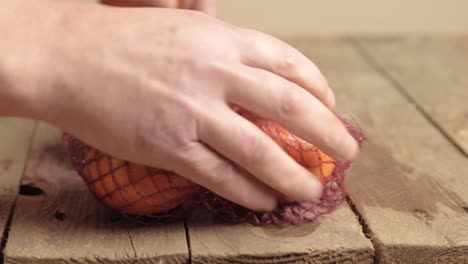 Hand-getting-of-fresh-clementine-oranges-in-netting-bag