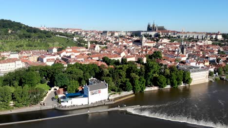 Sobrevuelo-Aéreo-Junto-Al-Río-Vltava-En-Praha,-República-Checa,-Con-Vistas-Al-Castillo-De-Praga,-Tejados-Rojos-De-Mala-Strana-Y-El-Puente-Charles-En-Una-Mañana-Soleada