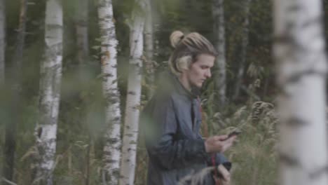 man using phone in a birch forest