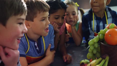 schoolkids looking at fruits in drawing class