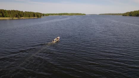 aerial view following a small fishing boat, in the sunny, archipelago of sweden