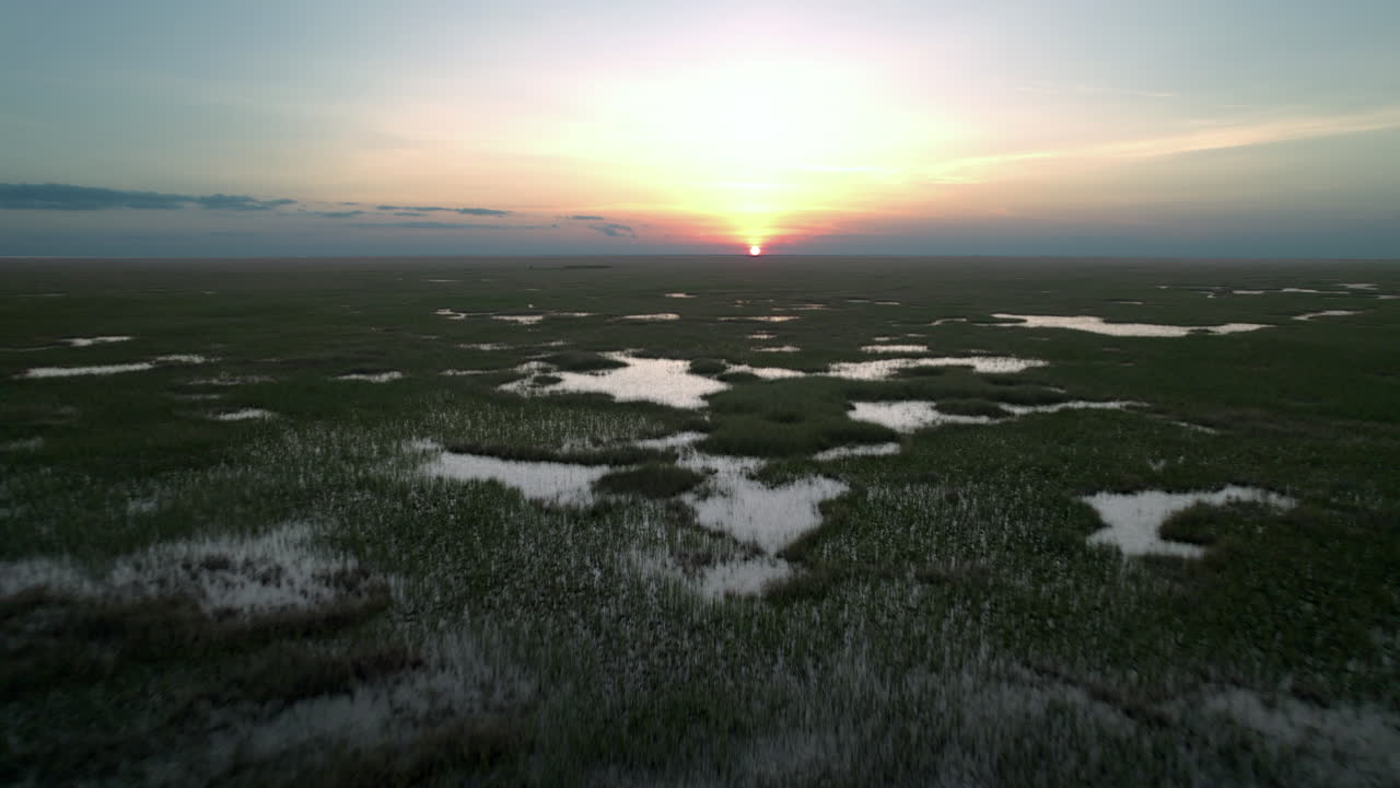 Evergladesin kosteikkosuo sahateräheinällä sadekauden auringonlaskun aikaan, ilmakuva.