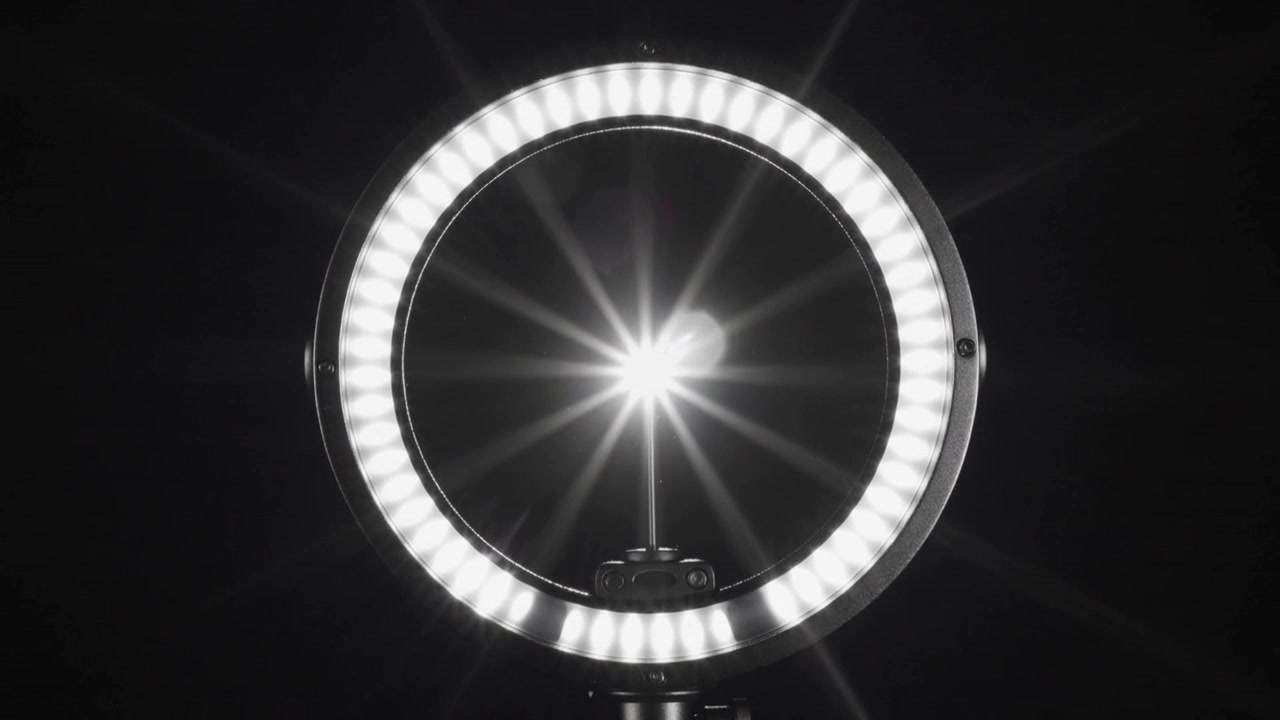 暗いスタジオでLEDリングライトの電源を入れるとスターバーストが発生し、サポートロッドとマウントはそのまま見える。
