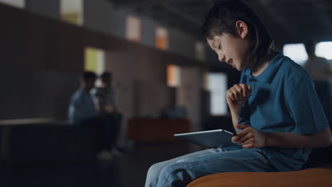 Focused-boy-using-pad-lose-in-online-game.-Pupil-with-gadget-ignoring-classmates