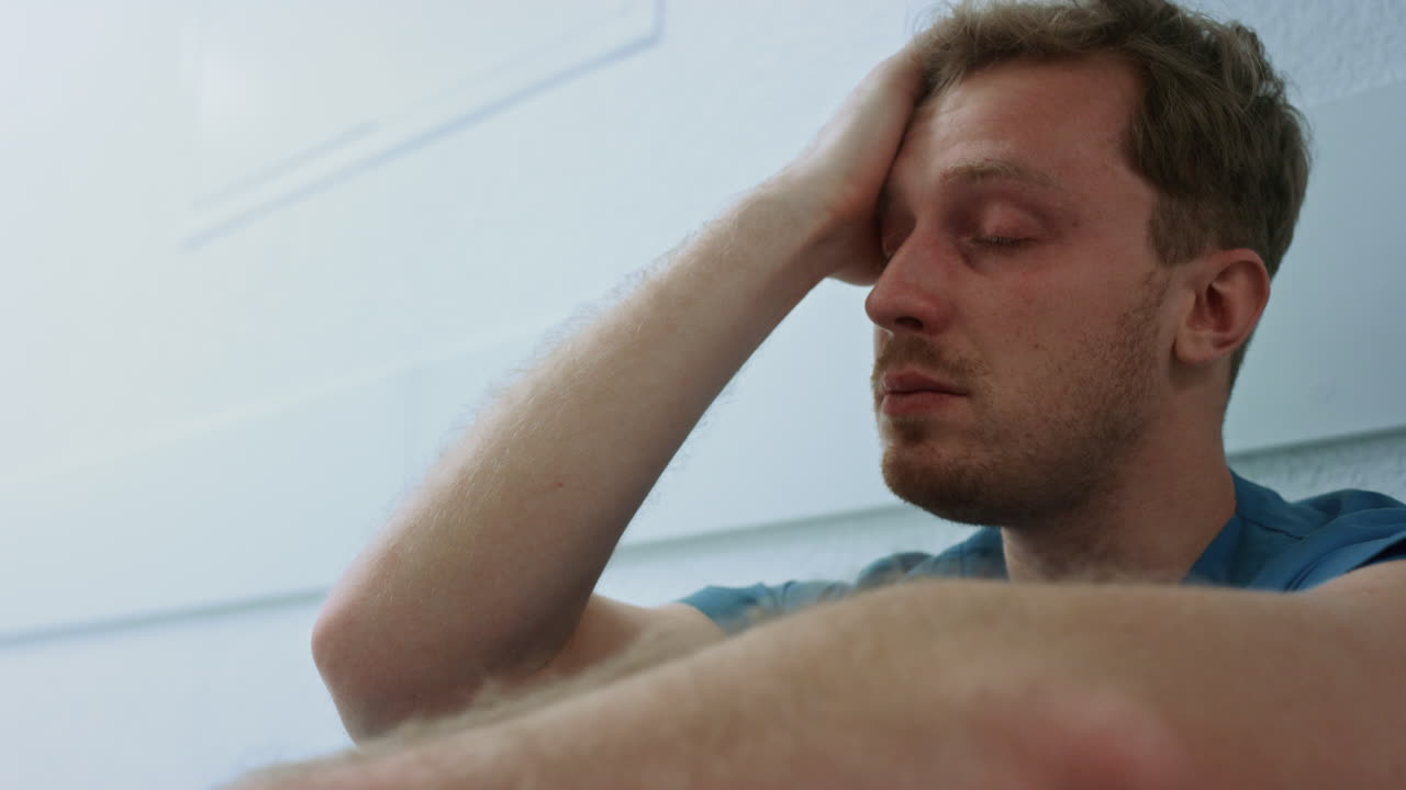 chirurgo sconvolto che guarda avanti seduto sul pavimento da vicino. medico stanco che si riposa da solo