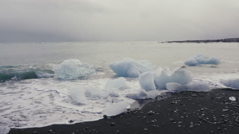 waves crashing at the bergy bits on the shore of glacier lake