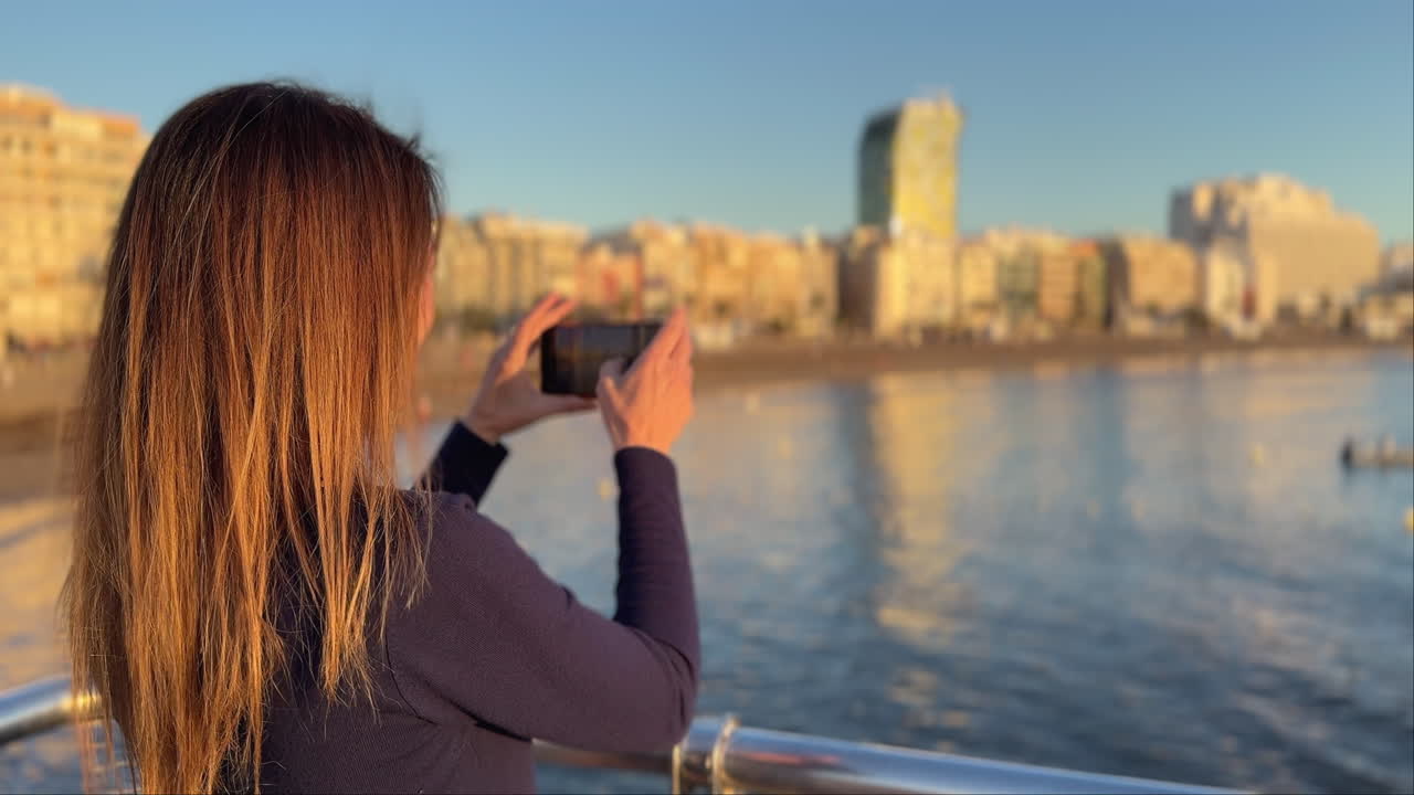 Woman taking pictures of Las Canteras beach in Gran Canaria at sunset, slow motion