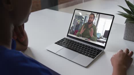 Mid-section-of-african-american-woman-having-a-video-call-on-laptop-with-male-colleague-at-office