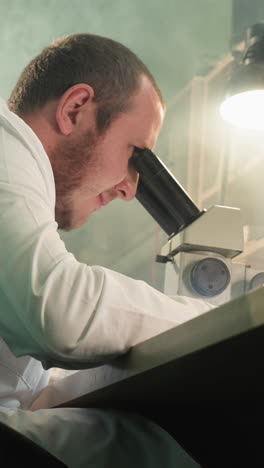 una vista de cerca de un técnico en una bata de laboratorio trabajando meticulosamente bajo un microscopio, inspeccionando una placa de circuitos electrónicos, con una lámpara de escritorio encendida se ha reflejado en la pantalla