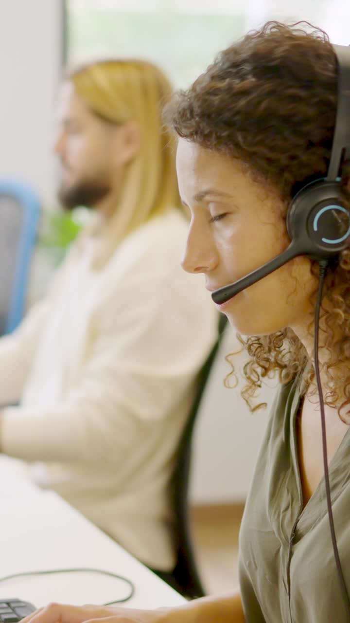 Concentrated woman using computer and headset in a coworking