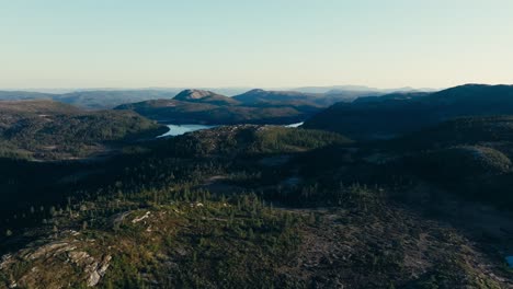 Mjøvatnet,-Indre-Fosen,-Trøndelag,-Norway---A-Lake-Surrounded-by-a-Rugged-Landscape-With-Forested-Hills-and-Distant-Mountains---Drone-Flying-Forward