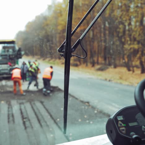 worker operating asphalt paver machine during road construction