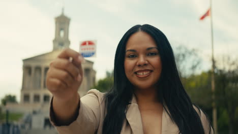 Woman holding I Voted sticker in front of Tennessee State Capitol