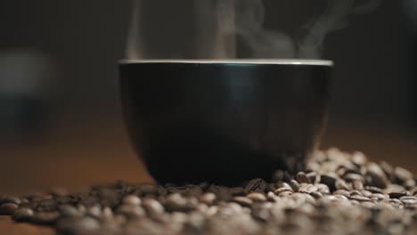 steam over a cup of coffee on a wooden table surrounded by fresh coffee beans slow motion