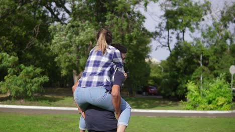 Handsome-african-guy-piggybacking-his-caucasian-happy-girlfriend-and-spinning-around-running-on-the-green-grass-in-the-sunny