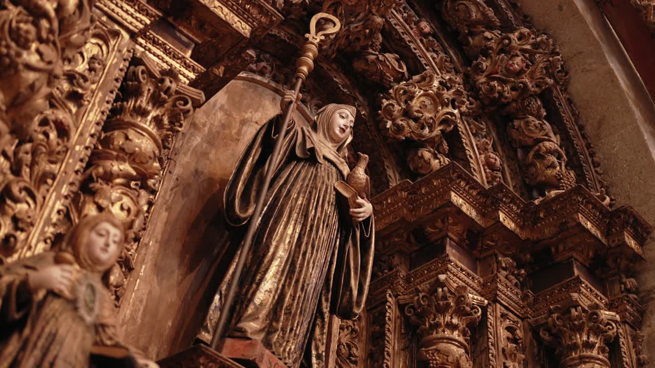gilded saint statue holding a crosier and chalice in an ornate altar