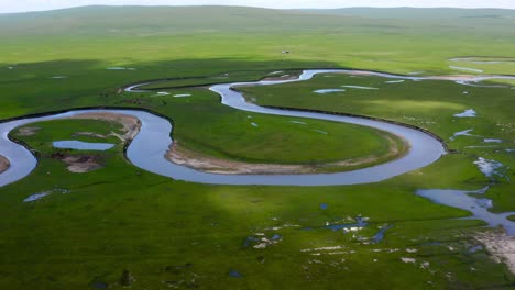 Winding-meandering-river-with-cloud-shadows-passing-by-oxbow-lake,-aerial