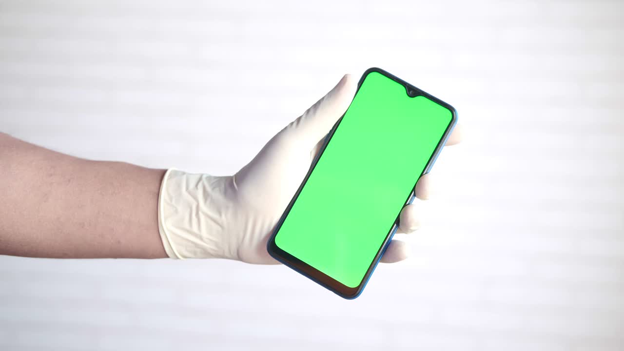 doctor's hand in protective gloves holding smart phone