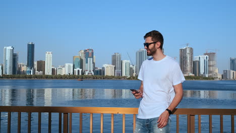 Happy-young-man-walking-on-the-street-and-looking-aside-while-talking-by-his-phone