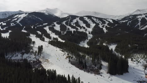 aerial drone footage of people skiing and snowboarding down the mountain in breckenridge, colorado