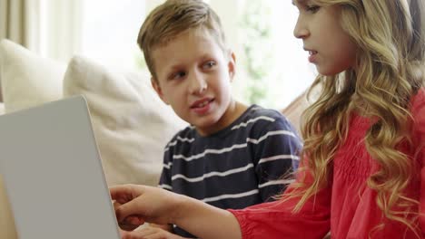 siblings using laptop in living room