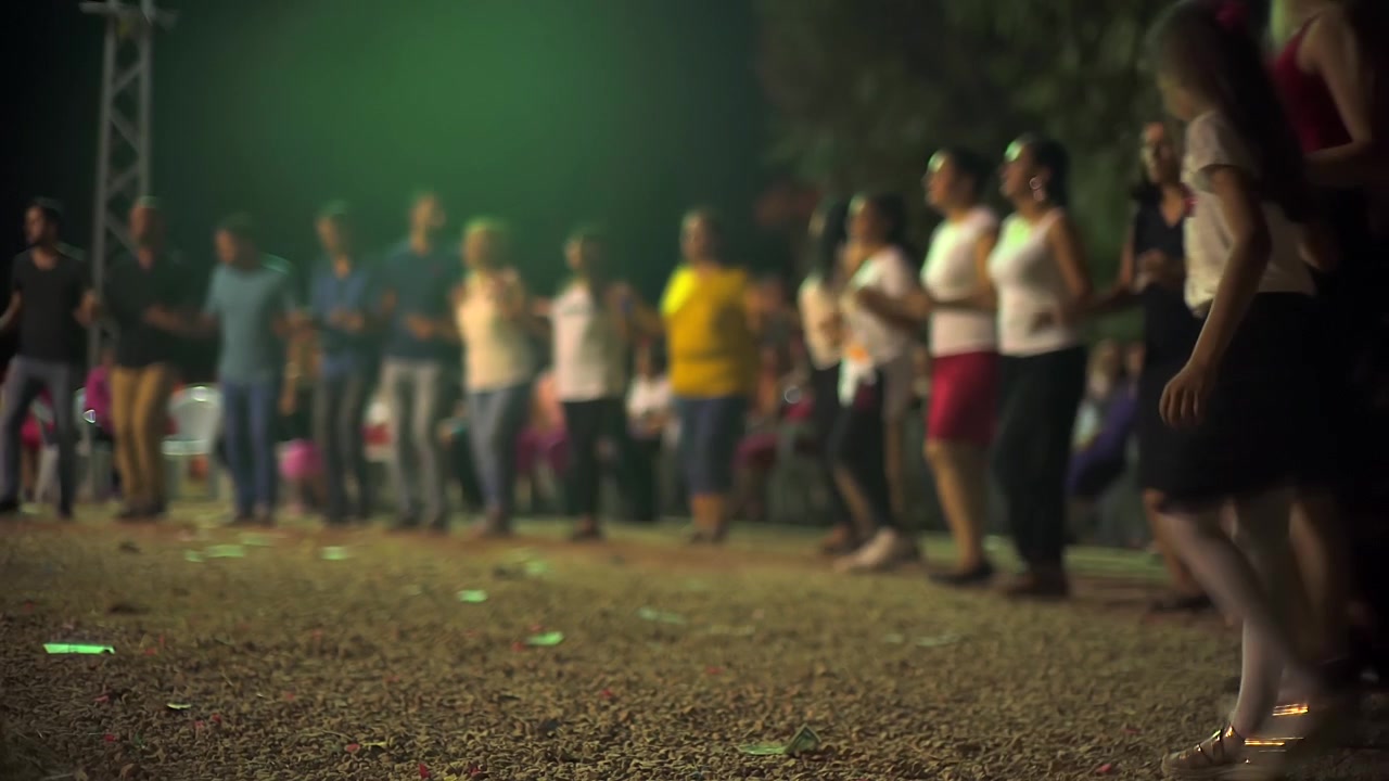 Gruppo di persone che ballano in cerchio di notte.