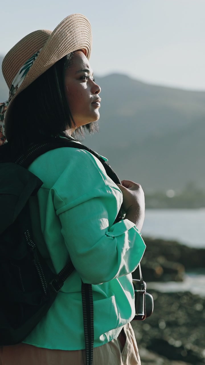 Young Woman Wearing a Straw Hat and Backpack Standing by the Ocean