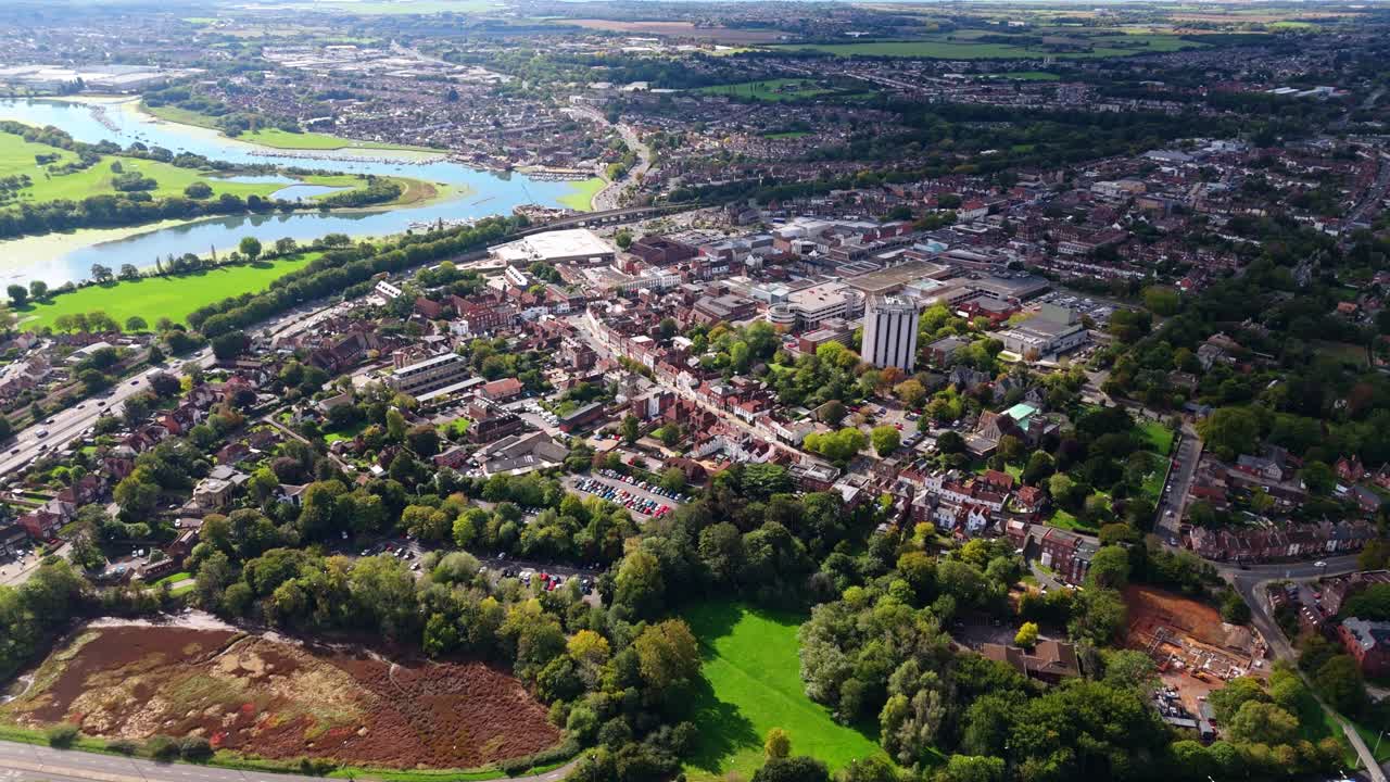 Aerial drone pans right over Fareham town, capturing river, trees, roads, and autumn colours glowing warmly in golden sunset light across the scenic English countryside landscape