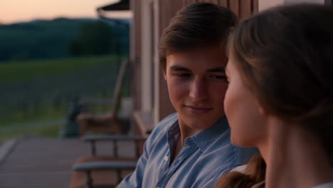a young couple sits together on a porch at dusk