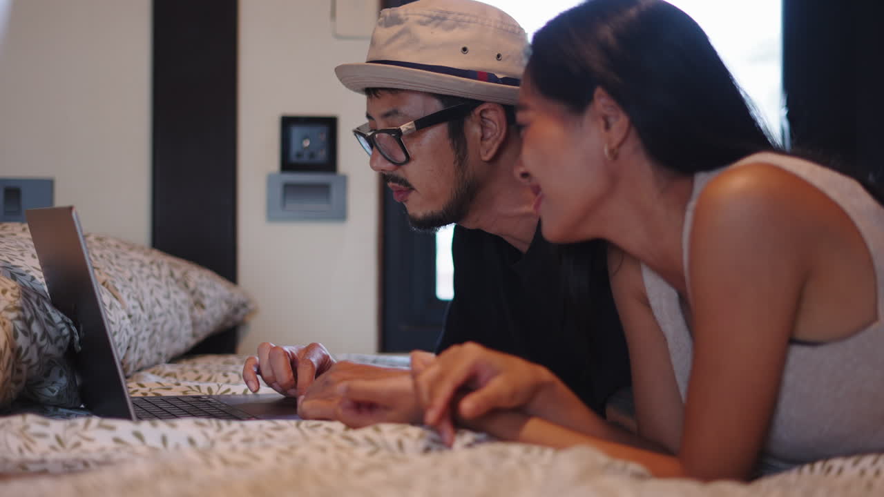 Couple using laptop in bed