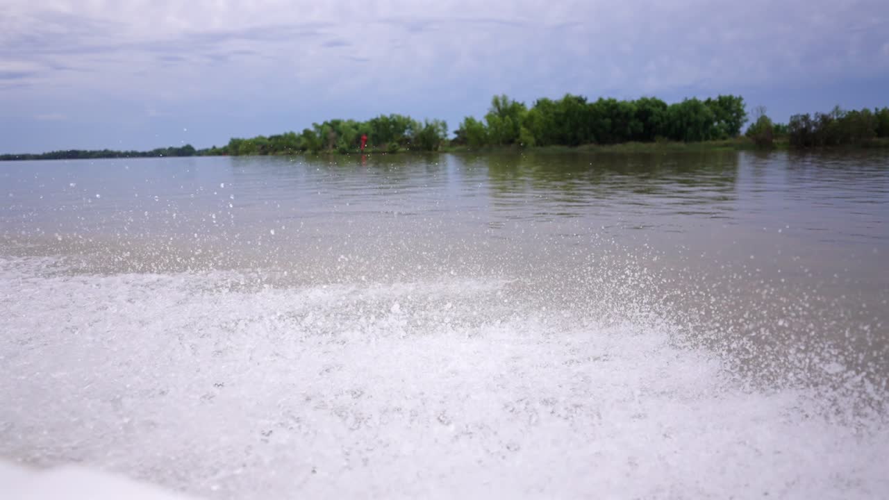 Wide open lake with rippling water splash from a moving motorboat in overcast weather