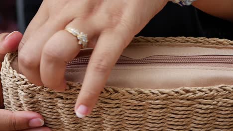 woman opening a straw woven handbag