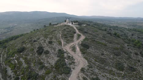 4k drone fly-by rápido sobre 2 antiguos molinos de viento reconstruidos en la cima de la colina al final de una carretera estrecha en alcublas, españa
